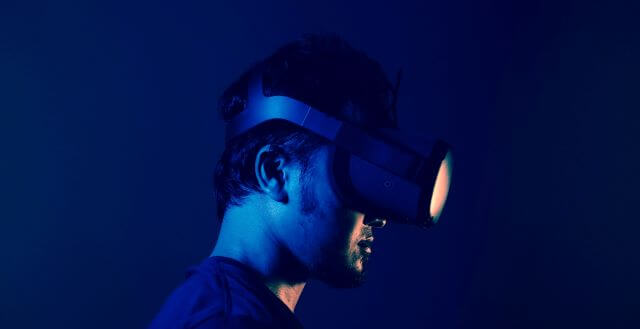 A guy enjoying Virtual reality using his vr headset in front of a blue background